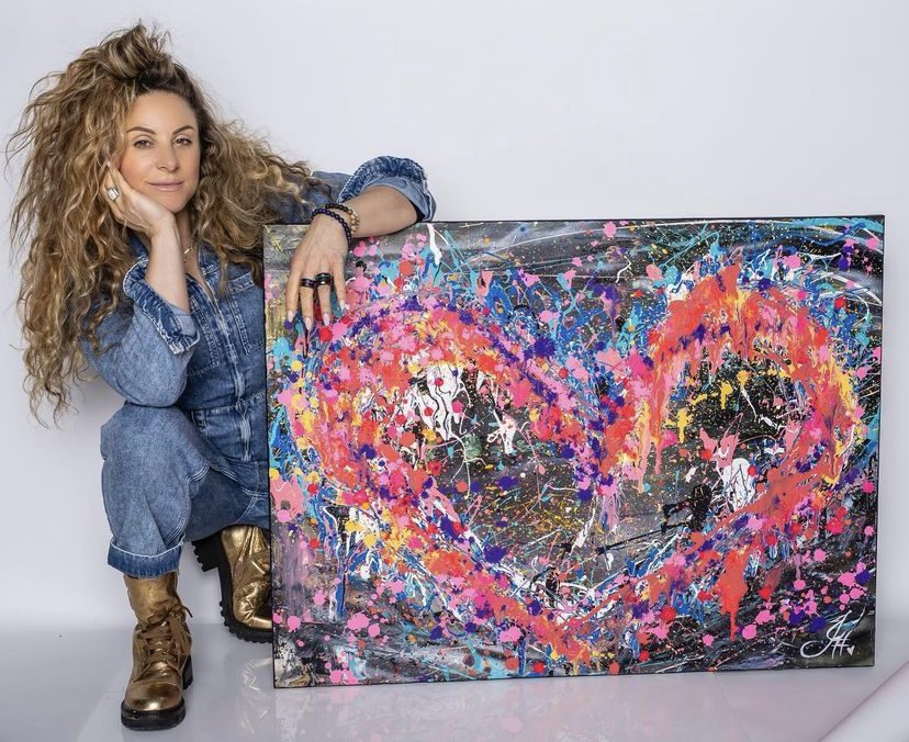 Jessica seated beside a large heart canvas in mixed media