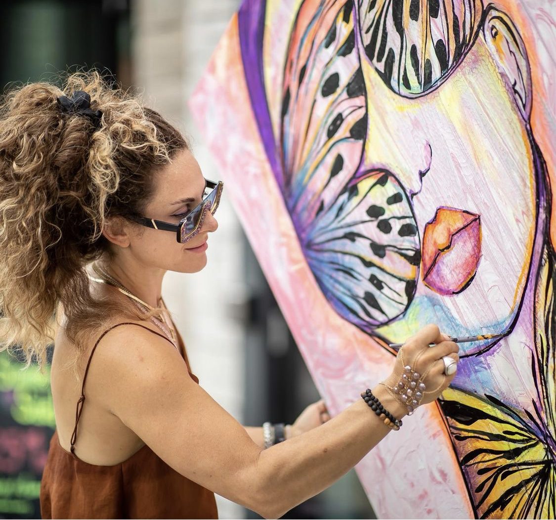 Jessica Gorlicky painting a large butterfly portrait in her studio