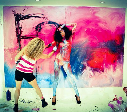Two performers painting a large canvas wall live