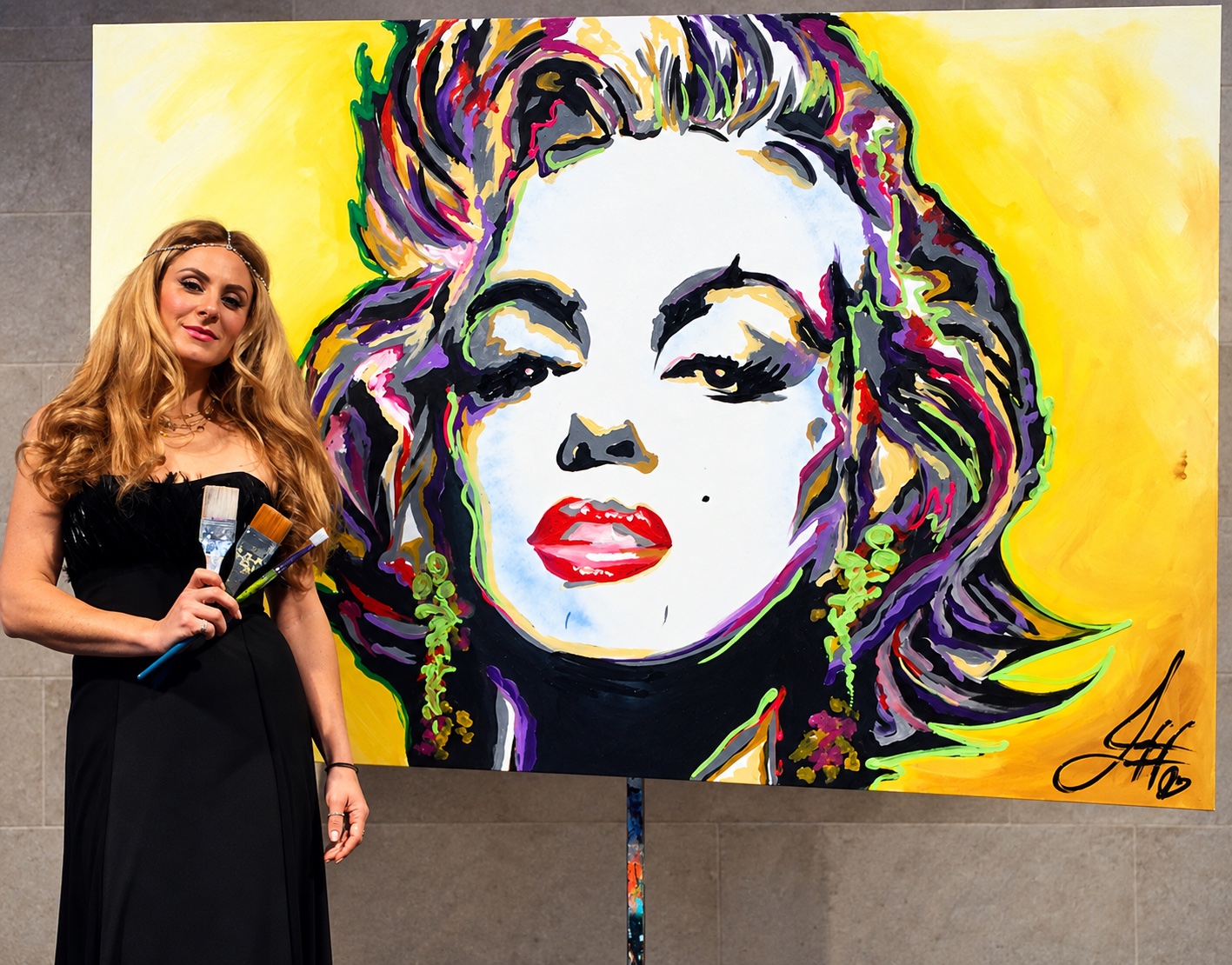 Jessica holding her brushes beside a large live painting of Marilyn Monroe
