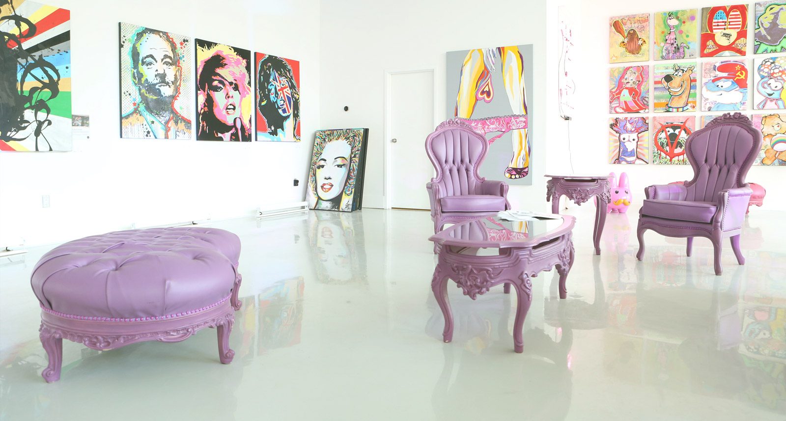 The gallery: white walls hung with pop art and purple lounge chairs